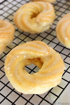 four glazed donuts sitting on top of a cooling rack