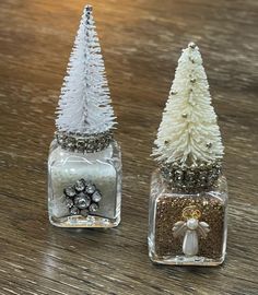 two small christmas trees sitting on top of a wooden table