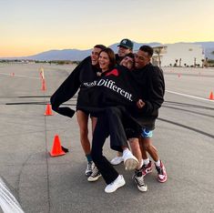 a group of people standing on top of an airport tarmac with their arms around each other