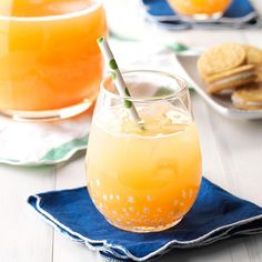 two glasses filled with orange juice on top of a blue napkin next to crackers