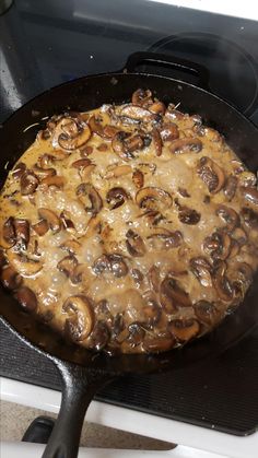 a skillet filled with mushrooms cooking on top of an oven burner in the kitchen