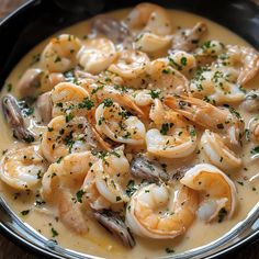 a bowl of shrimp and mushroom soup on a wooden table