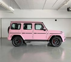 a pink jeep is parked in a large room with white walls and black rims