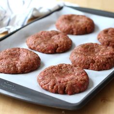 six hamburger patties on a baking tray ready to be cooked in the oven or baked