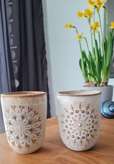 two vases sitting on top of a wooden table next to a potted plant