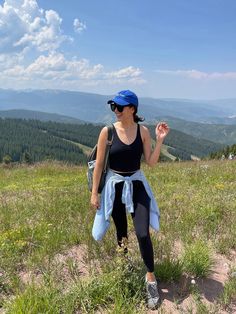 a woman standing on top of a lush green hillside