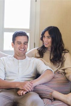 a man and woman sitting on a couch smiling at each other's eyeballs