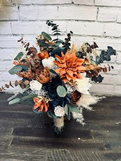 a bouquet of flowers sitting on top of a wooden table next to a brick wall