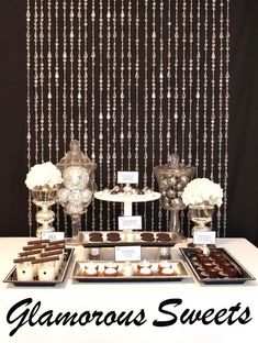 an assortment of desserts and sweets displayed on a table with beaded curtains behind them