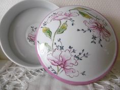 two plates with flowers painted on them sitting on a lace doily next to each other