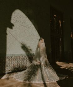 a woman in a wedding dress and veil standing on the ground near a white building