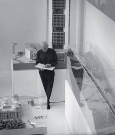 a man sitting on top of a table next to a tall building and looking at a book