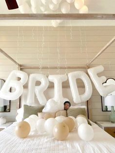 a bed with balloons that spell out the word bride on it and a person sitting at the foot of the bed