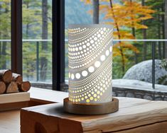 a wooden table with a lamp on it in front of a window and some logs