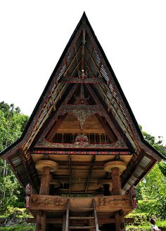 a tall wooden building sitting on top of a lush green field