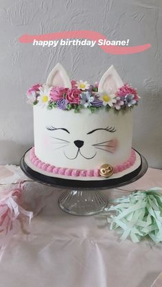 a birthday cake decorated with flowers and a cat's face