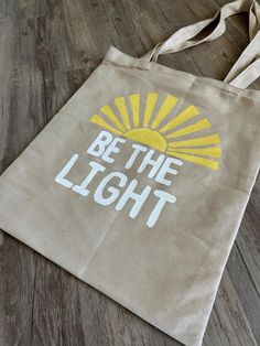 The perfect bag for shopping, carrying craft items, or bringing your Bible to church on Sunday! This hand-painted original design features the painted text "Be The Light" and a yellow sun. Painting Canvas Tote Bags, Bible Bag Painting, Painted Tote Bag Ideas Christian, Bible Bag Ideas, Jesus Tote Bag Painting Ideas, Simple Tote Bag Painting, Christian Tote Bag Design Diy Paint, Bible Bags Totes Diy Paint, Diy Bible Bag