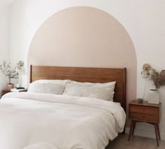 a bed with white sheets and pillows in a bedroom next to a wall mounted clock