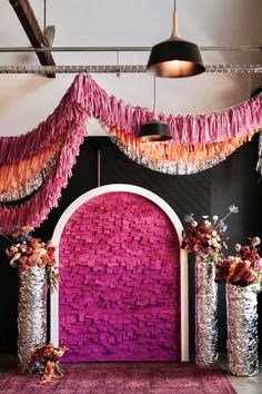 a pink and black room with decorations on the wall, vases filled with flowers