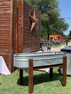 there is a large metal tub next to a wooden structure on the grass with tables and chairs around it