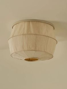 a white ceiling light hanging from the ceiling in a room with beige walls and flooring