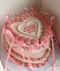 a heart shaped cake with pink icing and ribbon