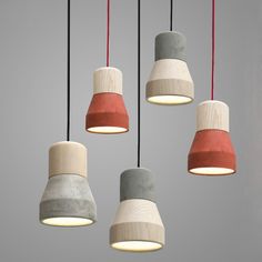 five different colored lamps hanging from the ceiling in a room with grey walls and red cords