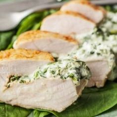 two slices of pork with spinach and cream sauce on a green leafy plate