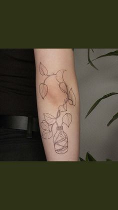 a person with a tattoo on their arm holding a vase filled with flowers and leaves