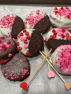 there are many cookies on the table with pink and red sprinkles around them