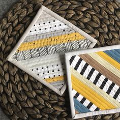 two quilted coasters sitting on top of a woven placemat next to each other