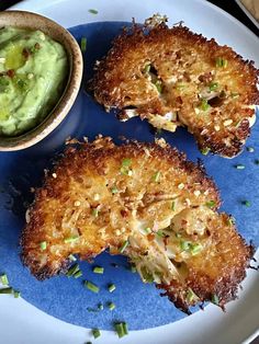 three fried chicken patties on a blue plate with a small bowl of guacamole