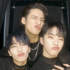 three young men standing next to each other in front of a car with their eyes closed