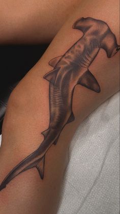 a black and white photo of a shark tattoo on the leg, done by an artist