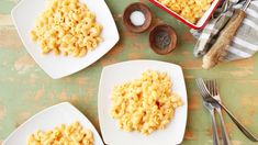 three plates filled with macaroni and cheese next to silverware on a table