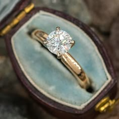 an engagement ring in a velvet box with gold trimmings and a diamond center