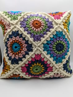 a multicolored crocheted pillow with a camera next to it