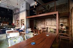 people are sitting at tables in an industrial style restaurant with brick walls and exposed ceilings