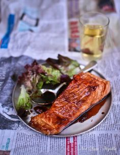 a plate with salmon, lettuce and salad on it next to a glass of water