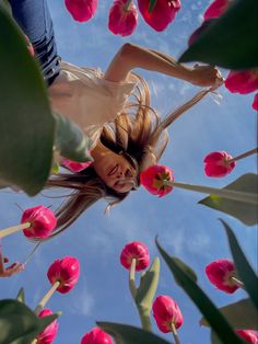 a woman is flying through the air among pink tulips with her hair blowing in the wind