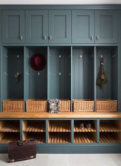 a large wooden bench sitting next to a wall filled with baskets and coats on it's sides