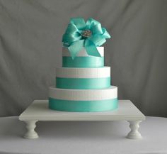 a three tiered cake with a large flower on the top and ribbon at the bottom