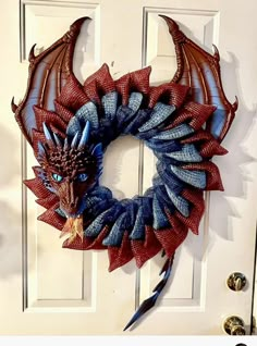 a red and blue dragon wreath hanging on a white door with the words, how to make a dragon wreath