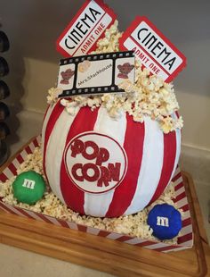 a popcorn bowl cake with two movie tickets on top and some candy in the middle