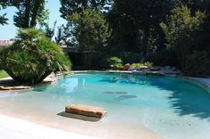 an empty swimming pool surrounded by lush green trees and rocks in the middle of it