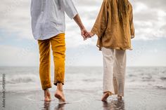 two people walking on the beach holding hands