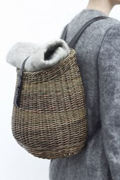 a woman carrying a wicker bag with a grey sweater on it's back