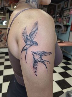 a woman with a tattoo on her shoulder and two birds in flight above her arm