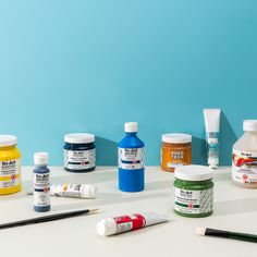 several different types of paint sitting on top of a white table next to each other