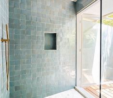 a bathroom with a glass shower door and tiled walls